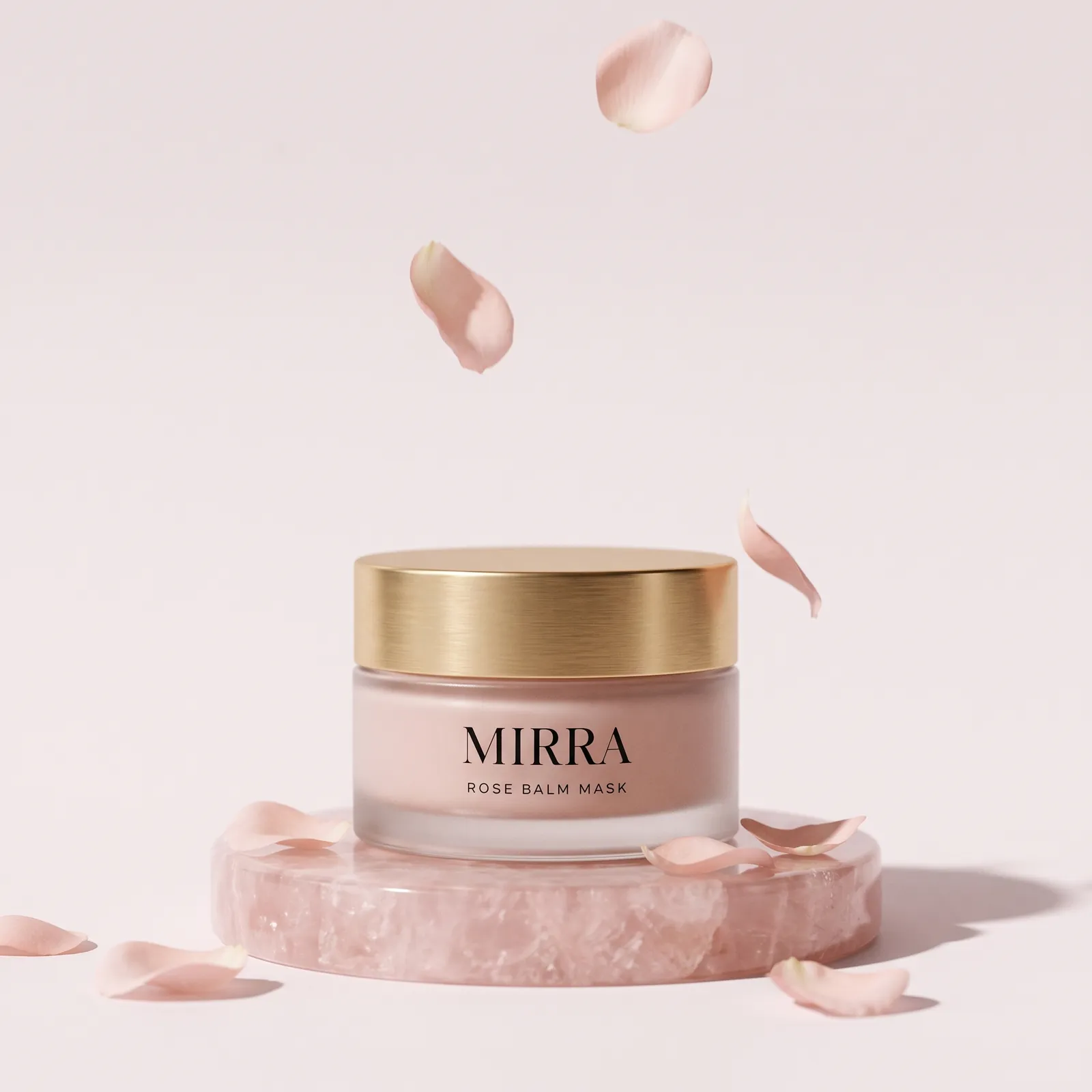 The Rose Balm Mask on a rose quartz plinth with falling petals